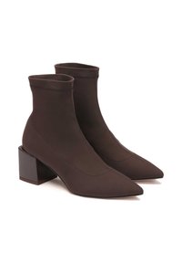 Botas de tobillo marrones hechas de material suave, con punta afilada, detalles de costura y un tacón cuadrado.