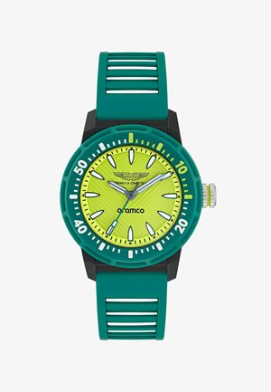 Fényes sárga óraszámlap texturált mintával, türkizgumi kerettel és szíjjal, ezüst alkatrészekkel és fehér órás jelölőkkel feketére festett tokozásban.