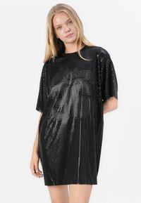 Crna sequined oversized haljina-t majica s natpisom "Glorious" i brojem "36" u podebljanom fontu, od mekog materijala s sjajnom teksturom.