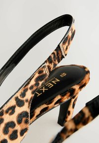 Chaussure à talon haut à bride arrière imprimé léopard avec semelle intérieure et talon noirs, nom de la marque "Next" visible à l'intérieur.