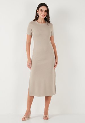 Beige midi dress with short sleeves, round neckline, and side slits. Smooth fabric texture. Simple silhouette, paired with light heeled sandals.