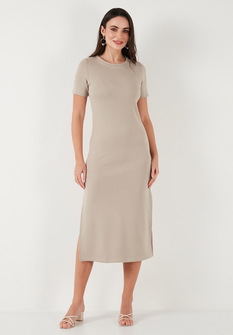 Beige midi dress with short sleeves, round neckline, and side slits. Smooth fabric texture. Simple silhouette, paired with light heeled sandals.