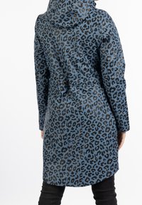 Manteau résistant à l'eau en bleu clair avec un motif léopard noir. Comprend une capuche et une taille réglable avec un cordon. Manches longues.