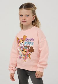 Felpa rosa con personaggi di cani dei cartoni animati e testo luccicante "BUON CAGNOLINI" e ulteriori dettagli. Il materiale sembra morbido e simile al pile.