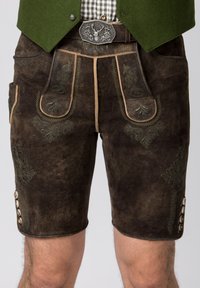 Pantaloni corti in pelle marrone con ricami verdi, due tasche frontali e bottoni decorativi sui lati. Finitura con una cintura tradizionale.