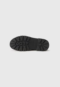 Black rubber shoe sole with deep treads and "ALDO" embossed in the center, isolated on a white background.