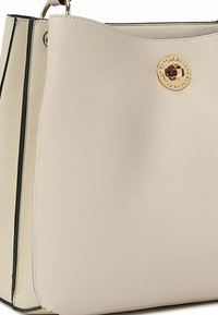 Borsa a tracolla in pelle beige con una texture liscia, dotata di un accento rotondo in metallo dorato e rifiniture nere lungo i bordi.