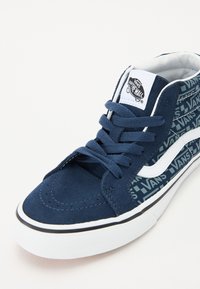 Námornícke modré vysoké tenisky vyrobené z semišu a plátna, so bielymi akcentmi, rovnými šnúrami a vzorovanou stranou s logom "VANS".