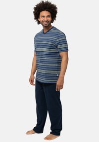 Gestreepte marineblauwe en blauwe katoenen T-shirt met V-hals, gecombineerd met donkere marineblauwe broek, met een ontspannen pasvorm en zachte textuur, zonder zichtbare merkaanduidingen.