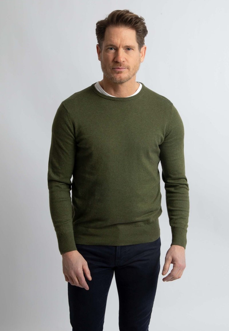 Khaki groene sweater met een ronde halslijn en lange mouwen, gemaakt van gebreide stof. Draag het over een wit T-shirt, gecombineerd met donkere broek.