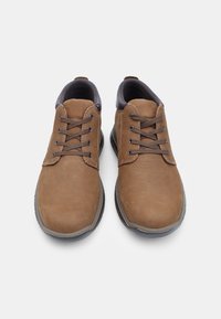 Pantofi din piele maro, cu o textură netedă, vârf rotund, design cu dantelă și talpă din cauciuc negru. Prezintă cusături și gauri pentru dantele maro.
