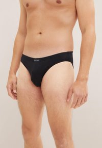 Slip neri in cotone con elastico in vita, dotati di etichetta sul davanti. Forma concisa progettata per comfort e vestibilità. Texture liscia.