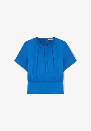 Blouse bleue à manches courtes avec encolure ronde, détails de tissu froncé à l'avant et large ceinture ajustée, posée à plat sur un fond blanc.