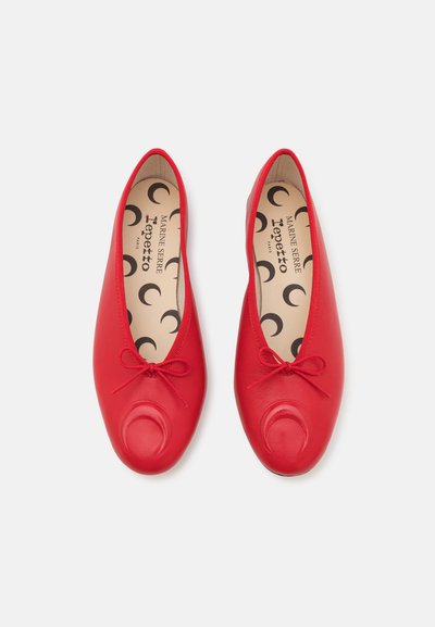 Red leather ballet flats with a rounded toe, decorative bow, and an inner sole featuring crescent moon patterns. Smooth texture throughout.