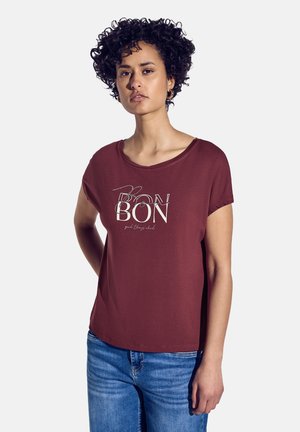 T-shirt court maroon à manches courtes avec une coupe ample, présentant un graphique blanc avec le mot "BON" et un accent textuel en dessous, fabriqué en tissu doux.