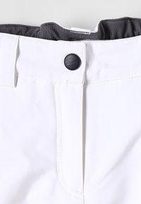 Bílé kalhoty mají hladký povrch, elastický pas s šedou vnitřní podšívkou a černé zapínání na knoflík s vyraženým logem.