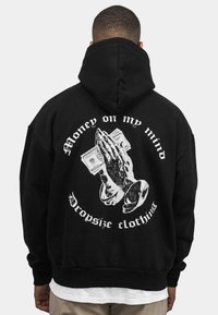 Juodas džemperis su grafika, kurioje pavaizduotos meldžiančios rankos laikantys pinigus, su užrašu "Pinigai mano mintyse" ir "Dropsize clothing" balta spalva.