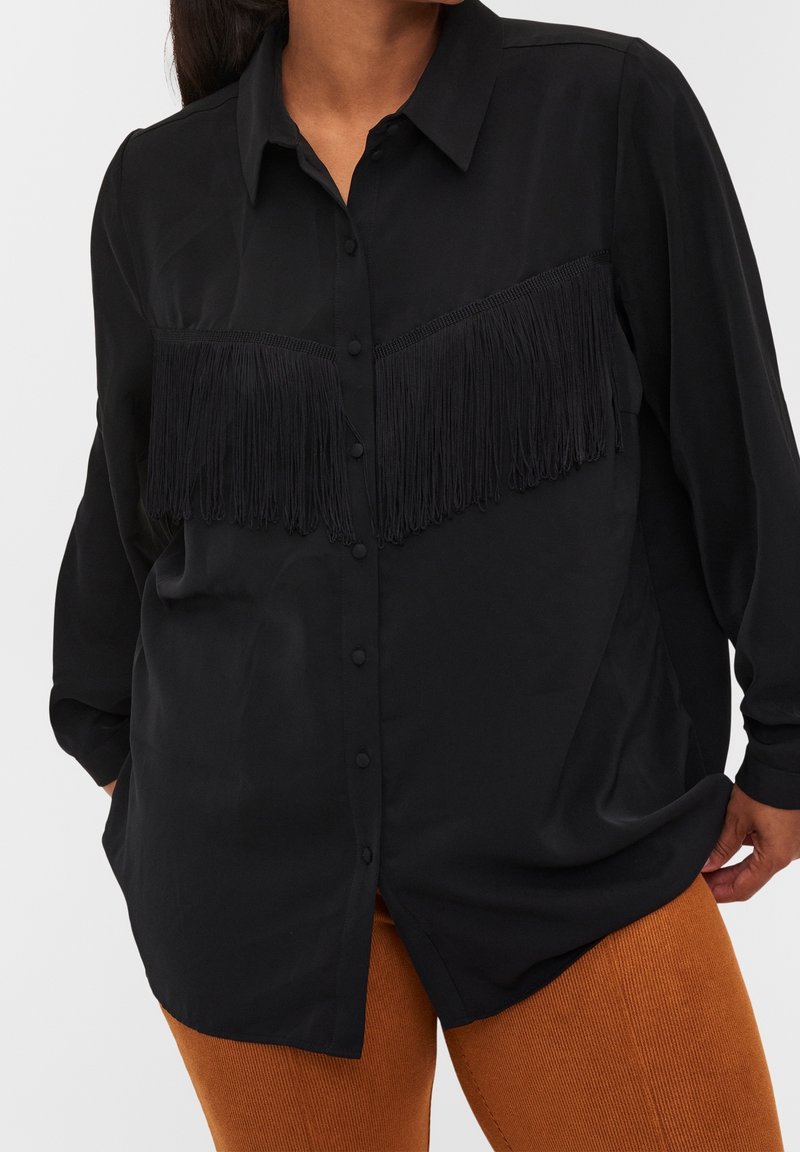 Chemise noire à boutons avec un design à franges sur la poitrine. Fabriquée en tissu lisse, avec des manches longues et un col standard.