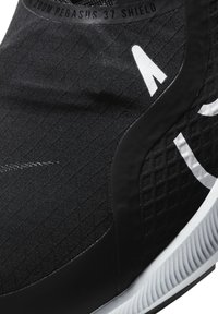 Gros plan de la chaussure de course Nike Zoom Pegasus 37 Shield noire avec logo blanc et semelle texturée.