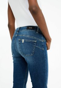 Jeans en denim bleu foncé de LIU JO, avec une coupe ajustée, une couture contrastée et une étiquette de marque au niveau de la taille, ainsi que des poches arrières.