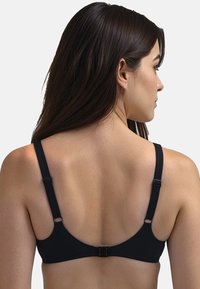 Mustat rintaliivit säädettävillä olkaimilla, sileää kangasta ja hakaskiinnitys takana. Minimalistinen muotoilu ilman näkyviä kuvioita.