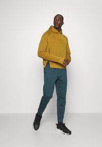 Nike Performance TAPER - Tracksuit bottoms - deep jungle