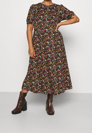 Floral midi dress in black with multicolored flowers, short puff sleeves, and a round neckline, paired with glossy brown heeled boots.