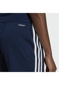 Laivastonsiniset urheilushortsit, joissa valkoiset korostevyöt, AEROREADY-logo vyötärönauhassa, sileä pinta ja räätälöity istuvuus.