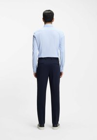 Vaaleansininen, pitkähihainen paita, jossa on ruutukuvio, yhdistetty tummansinisiin housuihin. Siinä on kärkipääntie ja napilliset kalvosimet; sileä pinta.