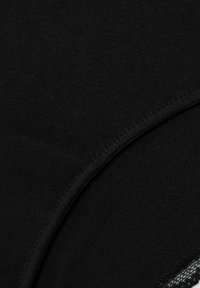 Close-up van zwarte stof met een gebogen naad en zichtbare stikdetails.