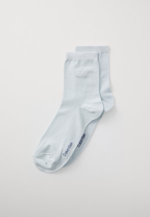 Svetlo modré ponožky po členky vyrobené z mäkkého materiálu. Majú hladkú textúru, rebrovaný manžet a vyšívané logo "ck" s textom "Calvin Klein".