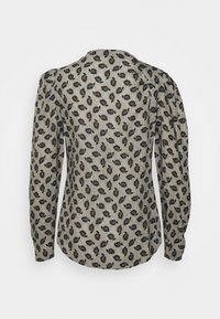 Blouse à manches longues en tissu beige avec un motif de feuilles noires. Caractérisée par un col rond et des manches froncées pour un aspect texturé.