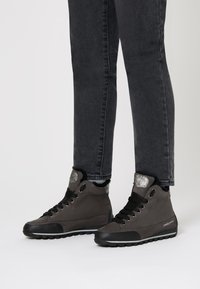 Sneakers alte nere realizzate in pelle texturizzata con un morbido colletto in pelliccia, dotate di accenti argentati, lacci spessi e suola in gomma.
