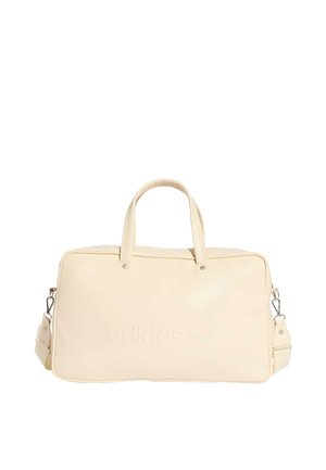 Sac de sport beige Adidas avec poignées supérieures, bandoulière amovible et logo embossé subtil à l'avant.