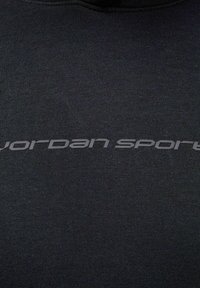Czarna bluza z teksturowanej tkaniny z widocznym szarym logo „jordan sport” na przodzie.