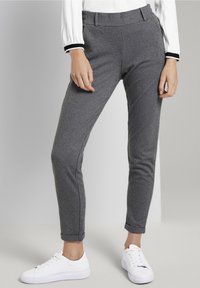 Spodnie w jodełkę w kolorze czarno-białym, o wysokim stanie, dopasowane i do kostek, zestawione z białymi trampkami.