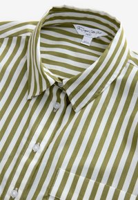 Camicia corta con strisce verticali verde oliva e bianche. Presenta una chiusura con bottoni sul davanti, un colletto e una tasca sul petto, con una texture del tessuto liscia.