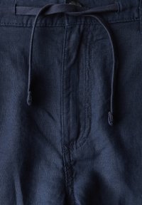 Námořnické modré lněné kalhoty s tahem na šňůrku, elegantním designem a měkkou strukturou s jemným leskem. Švy podél přední části.