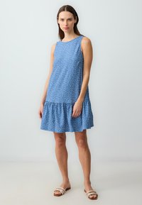 Abito senza maniche blu con pois bianchi, scollatura rotonda e orlo arricciato. Realizzato in tessuto leggero, presenta una vestibilità comoda e un design informale.