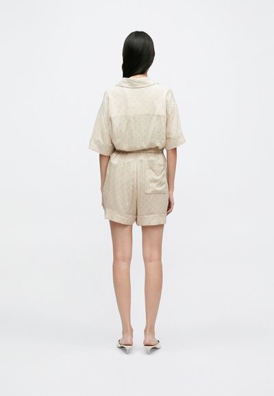 Kratký béžový outfit z textúrovanej látky s diamantovými vzormi, s krátkymi rukávmi a voľným strihom, elastickým pásom a zadnou vreckom.