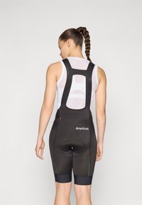 Sorte sykkeldress med justerbare stropper, teksturert stoff, polstret seteområde og reflekterende detaljer. Merkevarenavn "GripGrab" vises.