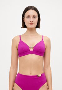 Roza bikini gornji dio s trokutastim oblikom, teksturiranim uzorkom i metalnim detaljem u središtu. Podesive naramenice i odgovarajući visokoprofilni donji dio.