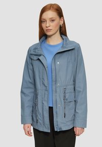 Giacca azzurra chiara con zip frontale, coulisse regolabili e tasche. Caratterizzata da un cappuccio e da una vestibilità casual e rilassata.