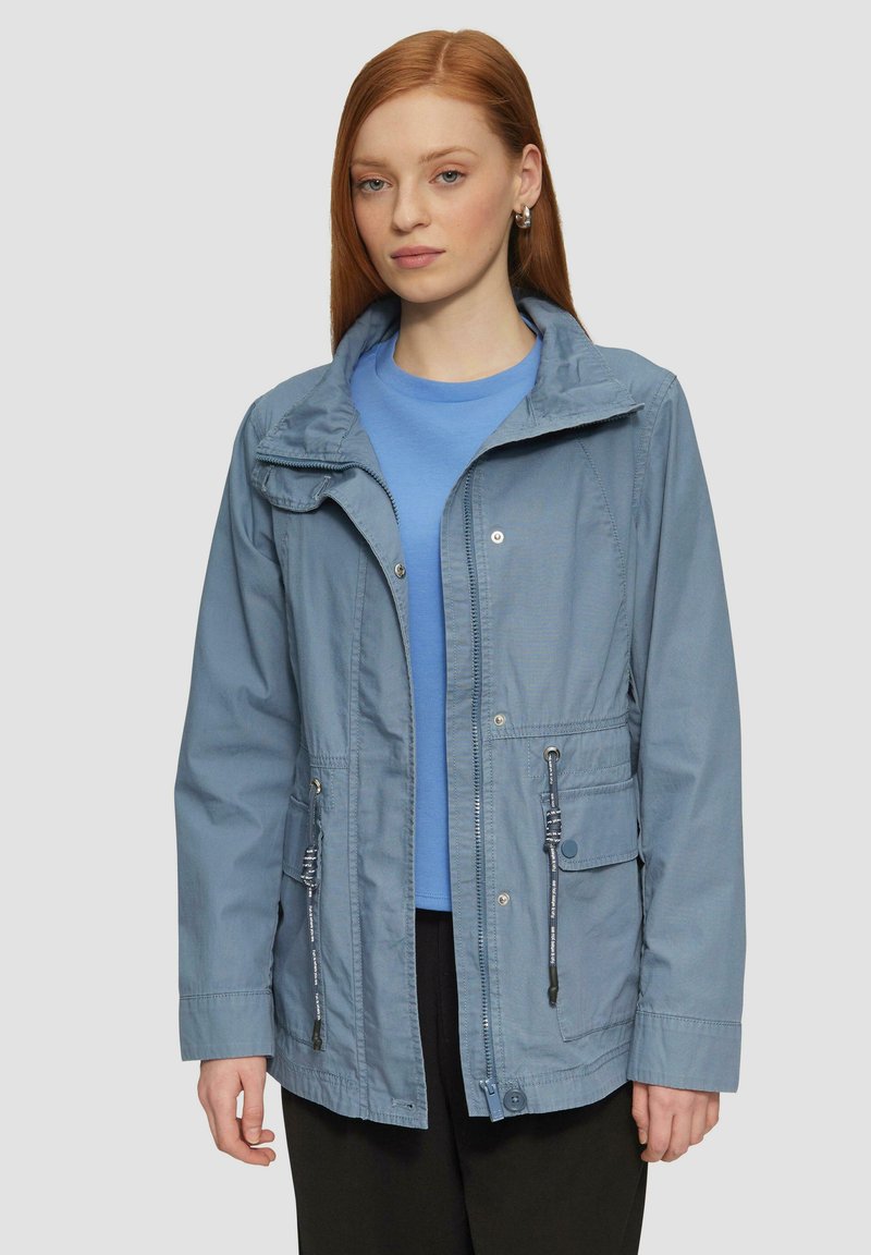 Giacca azzurra chiara con zip frontale, coulisse regolabili e tasche. Caratterizzata da un cappuccio e da una vestibilità casual e rilassata.