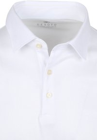 Witte polo met een klassieke kraag, twee crèmekleurige knopen en een gestructureerde stof, met een label met de "DESOTO" branding aan de binnenkant van de kraag.