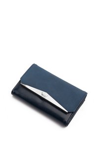 Navy leather wallet with a matte finish, silver angular accent, and a fold-over design. Smooth texture with contrasting shades.