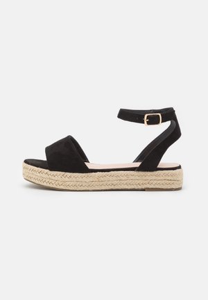 Sort ruskindssandal med en justerbar ankelrem, espadrille-stil jute mellemsål og en platformbund for ekstra højde.