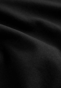 Tessuto nero con una superficie liscia, caratterizzato da onde e pieghe sottili, che evidenziano il suo materiale morbido ed elastico.