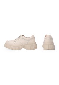 Hellbeige Sneaker mit abgerundeter Zehenpartie, Schnürverschluss und dickem, geripptem Profil. Sleek Obermaterial aus Leder mit subtilen Nähakzenten.