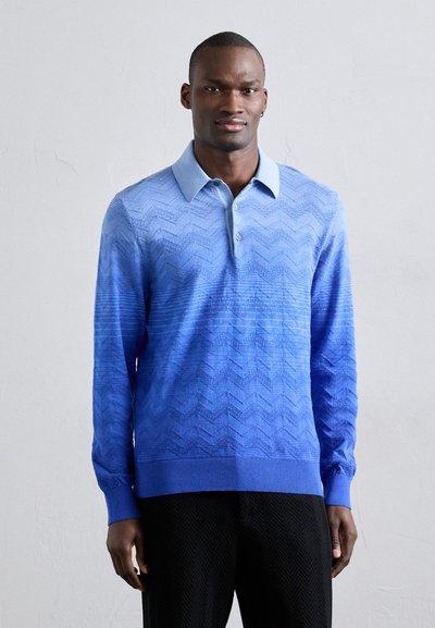 Blaues Langarm-Polo mit einem Farbverlauf in Chevron-Muster, ausgestattet mit einem Kragen und Knopfleiste mit drei Knöpfen. Aus strukturierter Stoff gefertigt.